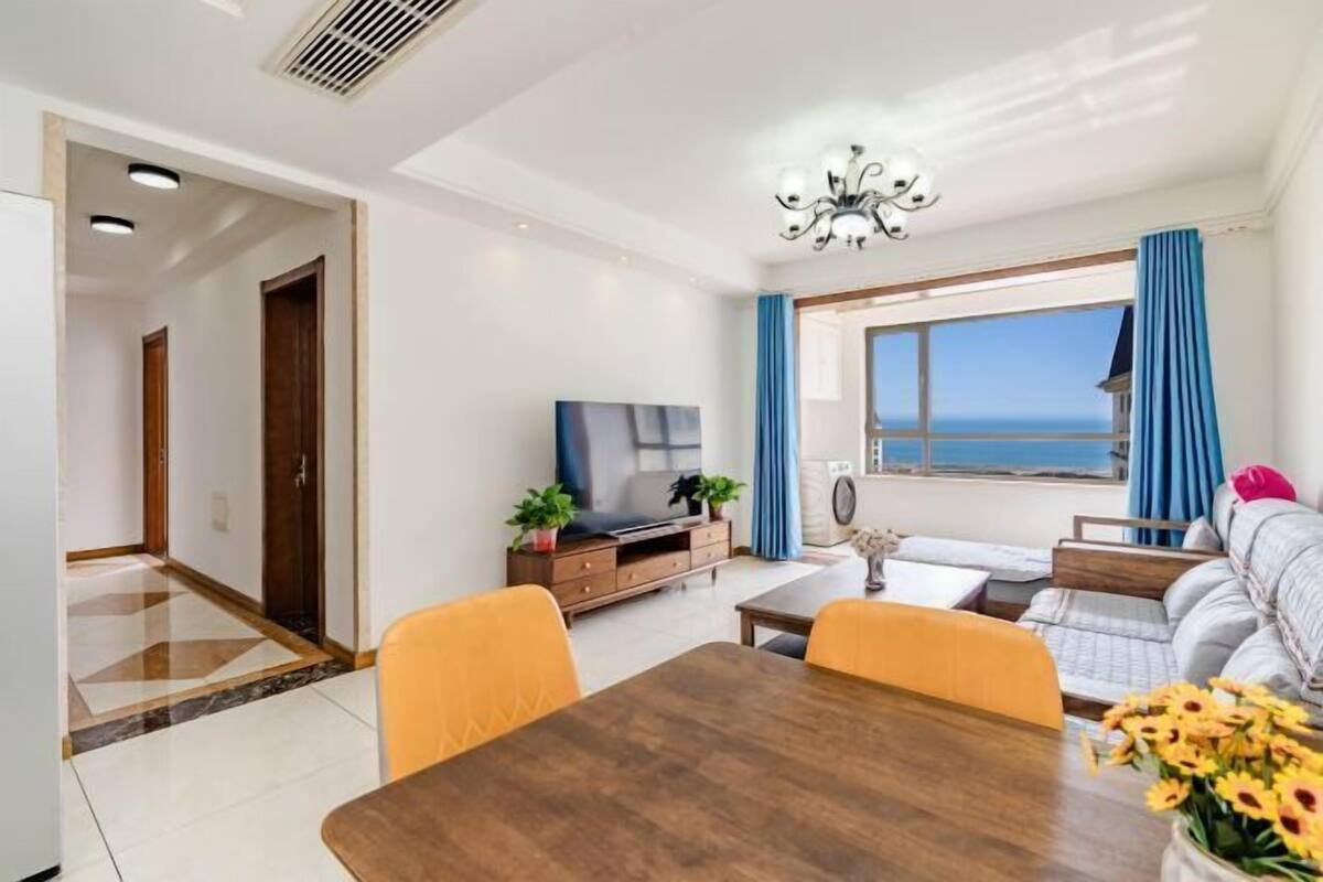A modern living room with a dining table, sofa, and TV.