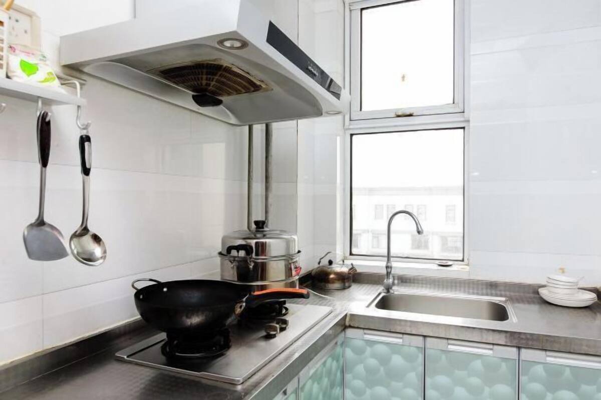 A modern kitchen with a stove, pots, a window, and a sink.