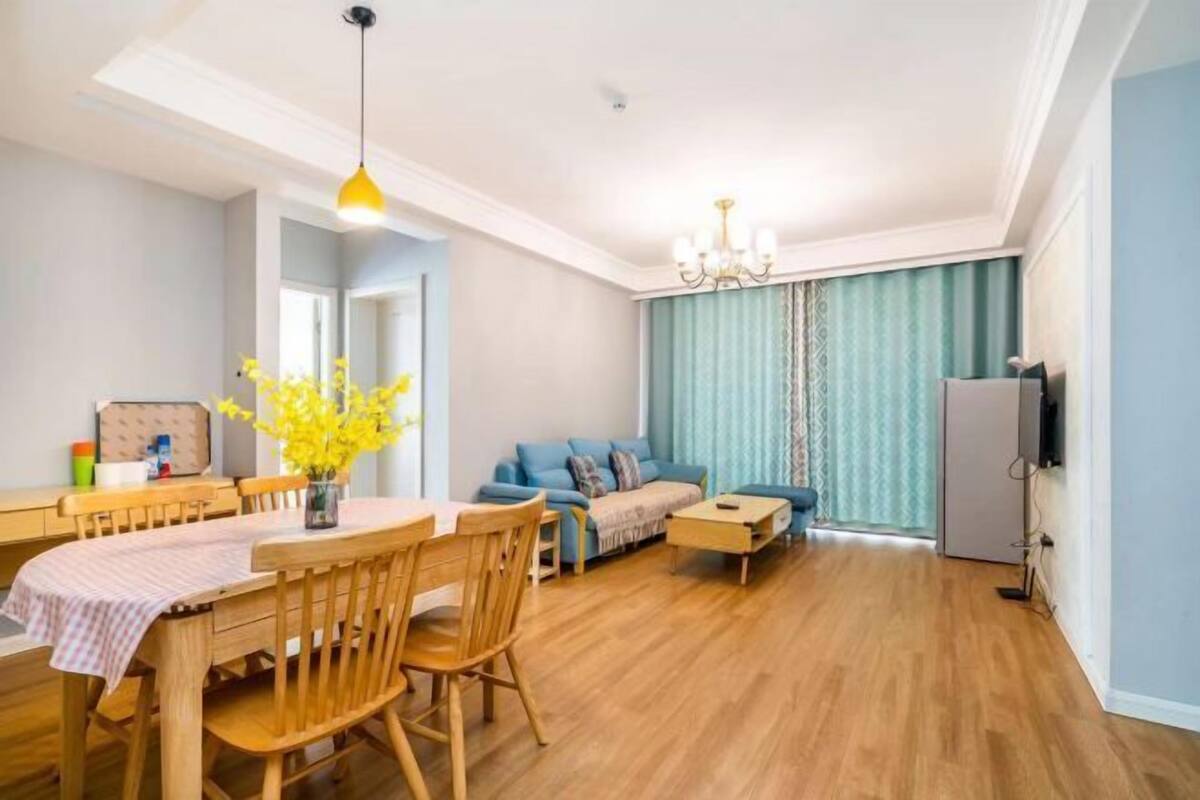 A living room with a sofa, a dining table with chairs, a chandelier, and a television.