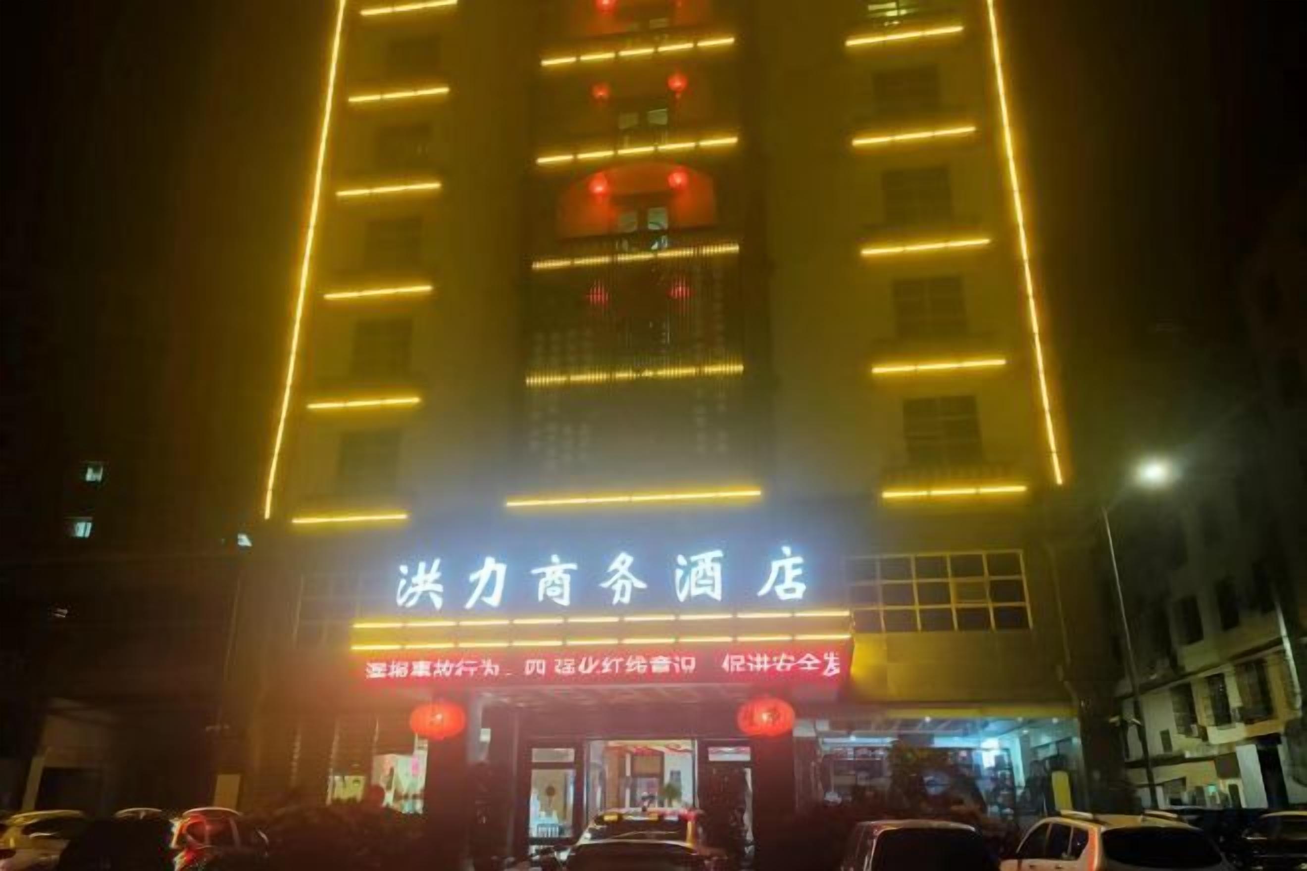 Um hotel com um letreiro iluminado e entrada visível.