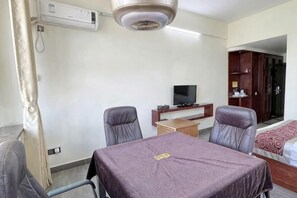 Ein Hotelzimmer mit Bett, Fernseher, Schreibtisch und Stuhl.