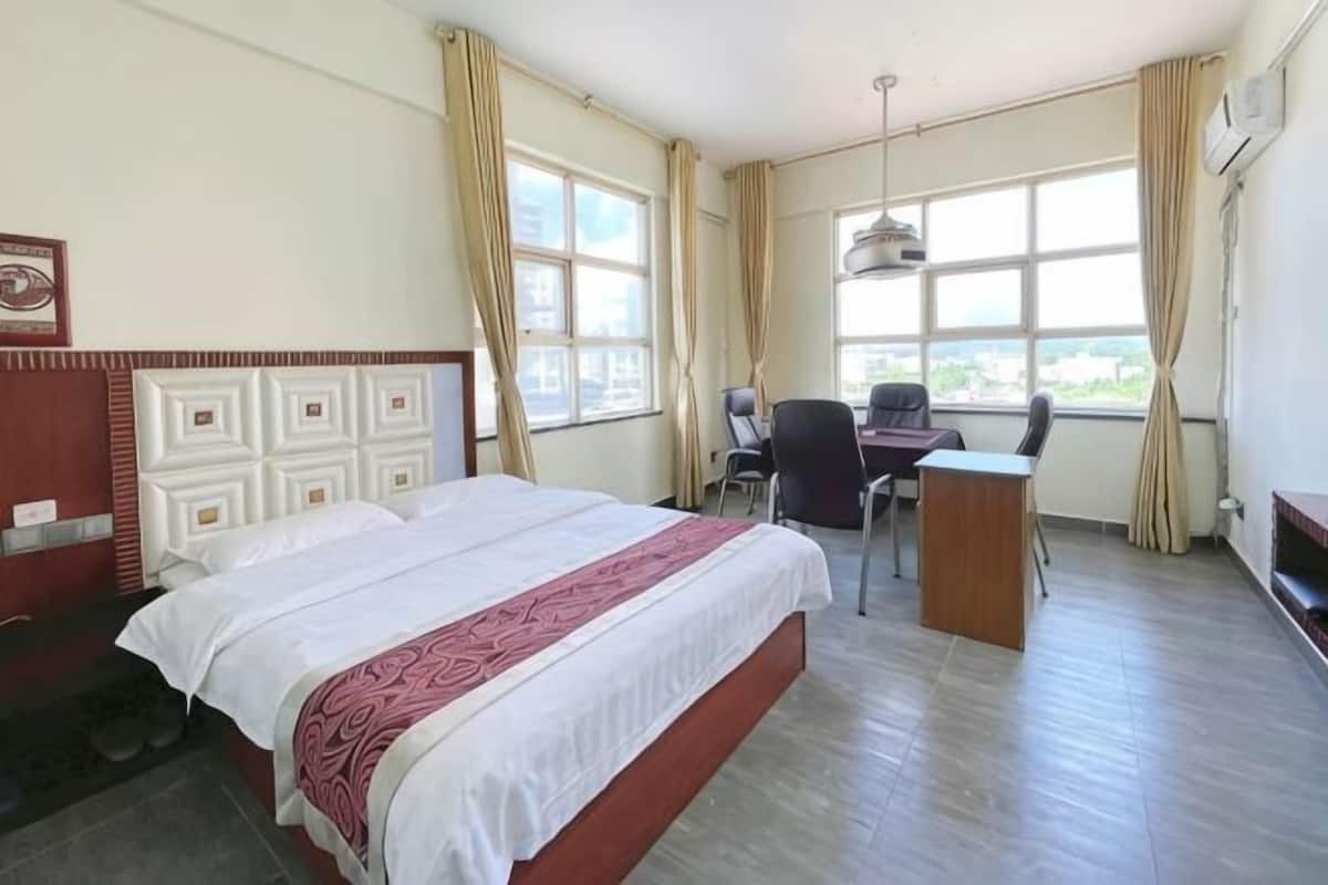 A hotel room with a large bed, a desk, and a chair.