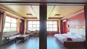 A hotel room with a bed, a sofa, a table, and chairs. - Hongli Business Hotel (Tunchang)