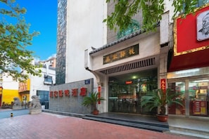 A hotel entrance with a traditional Chinese architectural style, a red awning, and potted plants. - Wujia Yizhan Boutique Inn (Zhengzhou)