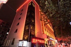 Een meerhoog gebouw met een opvallende verticale structuur en een gevel die rood verlicht is.