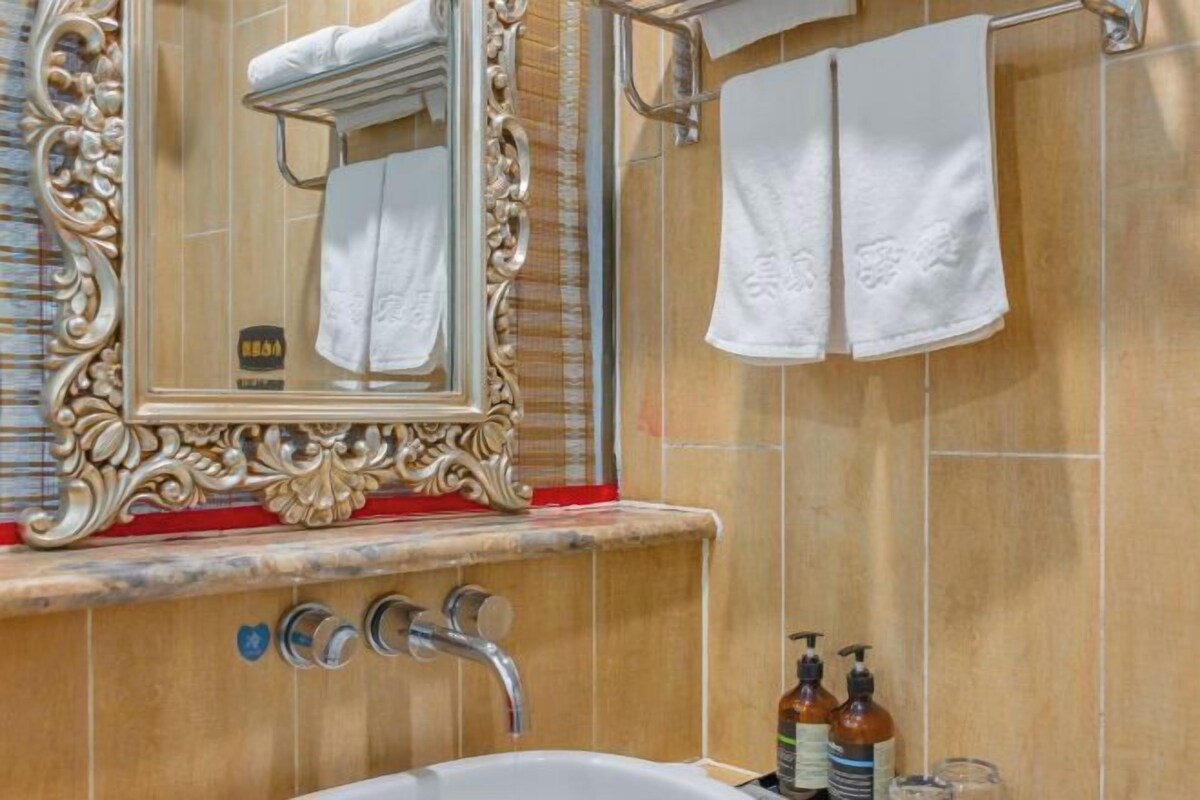 A bathroom with a large ornate mirror, a bathtub, and two hand soap dispensers.