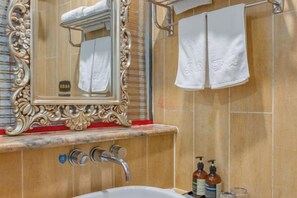 Ein Badezimmer mit einem großen, verzierten Spiegel, einer Badewanne und zwei Seifenspendern.