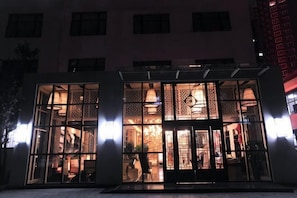 Un edificio con amplios ventanales, una entrada visible y una puerta con un portón decorativo.