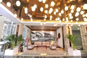 A lobby with a seating area, a large wall mural, and hanging lights. - Wujia Yizhan Boutique Inn (Zhengzhou)