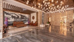 Um hall amplo com piso de mármore, mobiliário de madeira e um grande mural na parede.