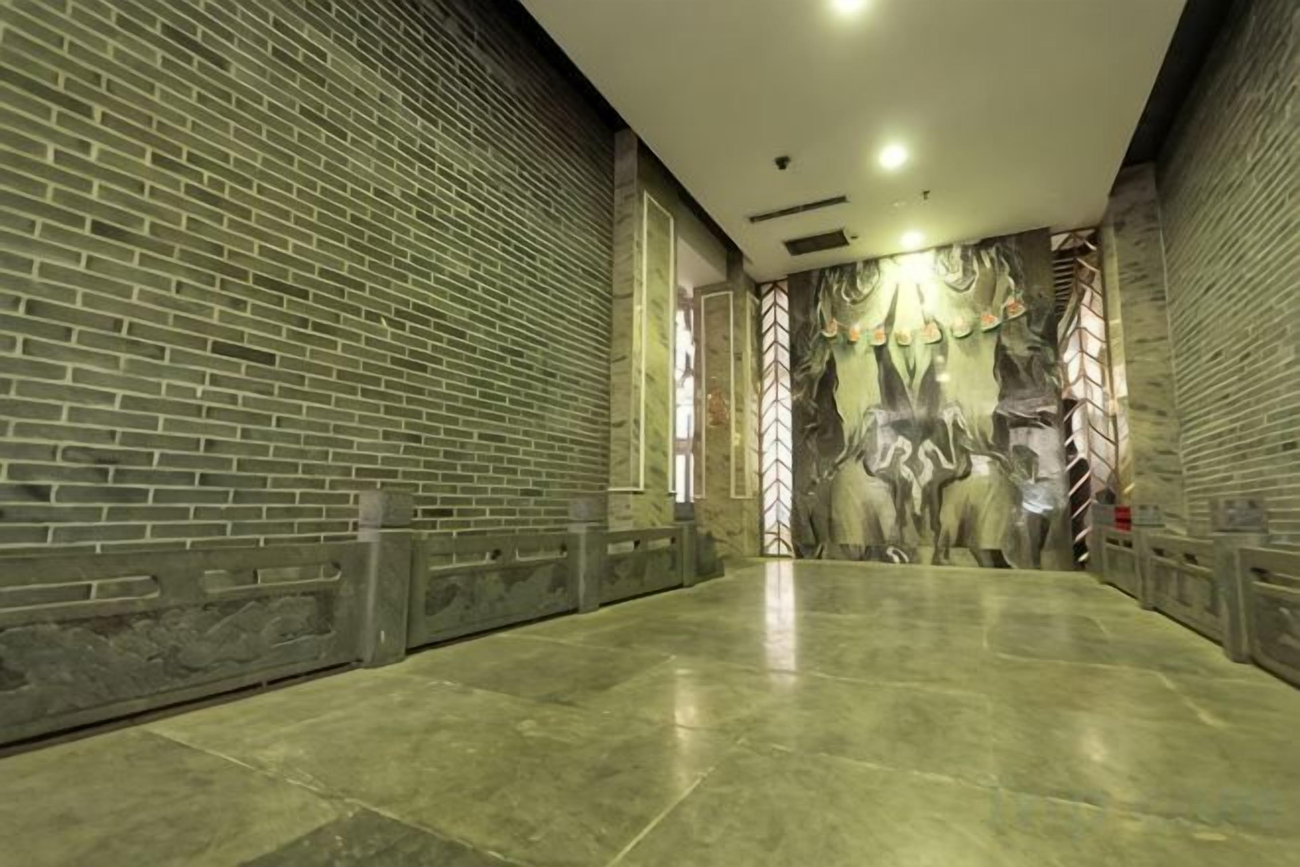 A corridor with a brick wall on one side and a mural on the other.