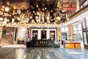 Eine Hotellobby mit einer Rezeption, einem Automaten und einer Treppe zu einer weiteren Etage.