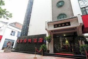 Ein Hotel Eingang mit traditioneller chinesischer Architektur, einer großen Säule und einem Schild mit chinesischen Schriftzeichen.