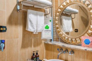 A bathroom with a sink, two faucets, a mirror with a decorative frame, and a towel rack with towels. - Wujia Yizhan Boutique Inn (Zhengzhou)
