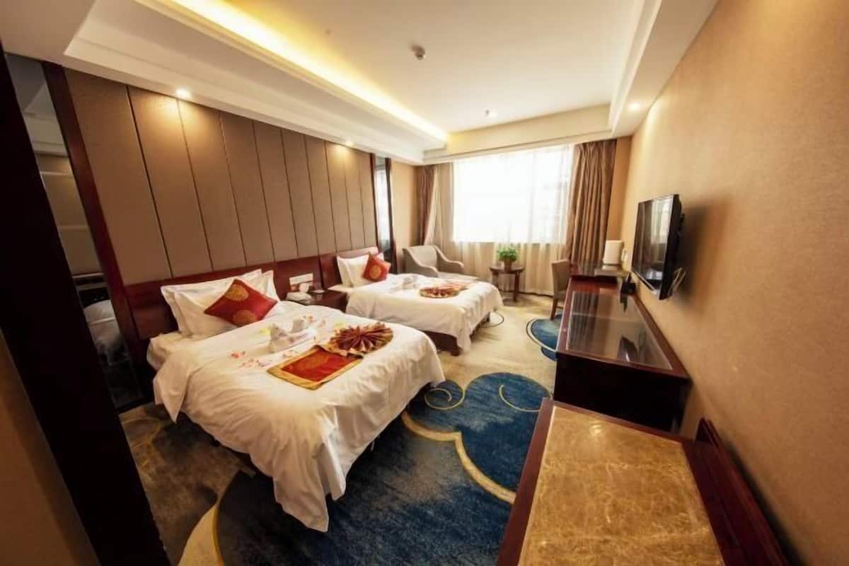 Una habitación de hotel con dos camas, televisión y un pequeño escritorio.