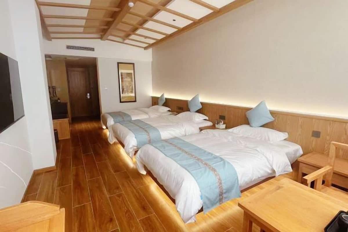 Habitación de hotel con dos camas, piso y techo de madera, una pequeña mesa y una silla.