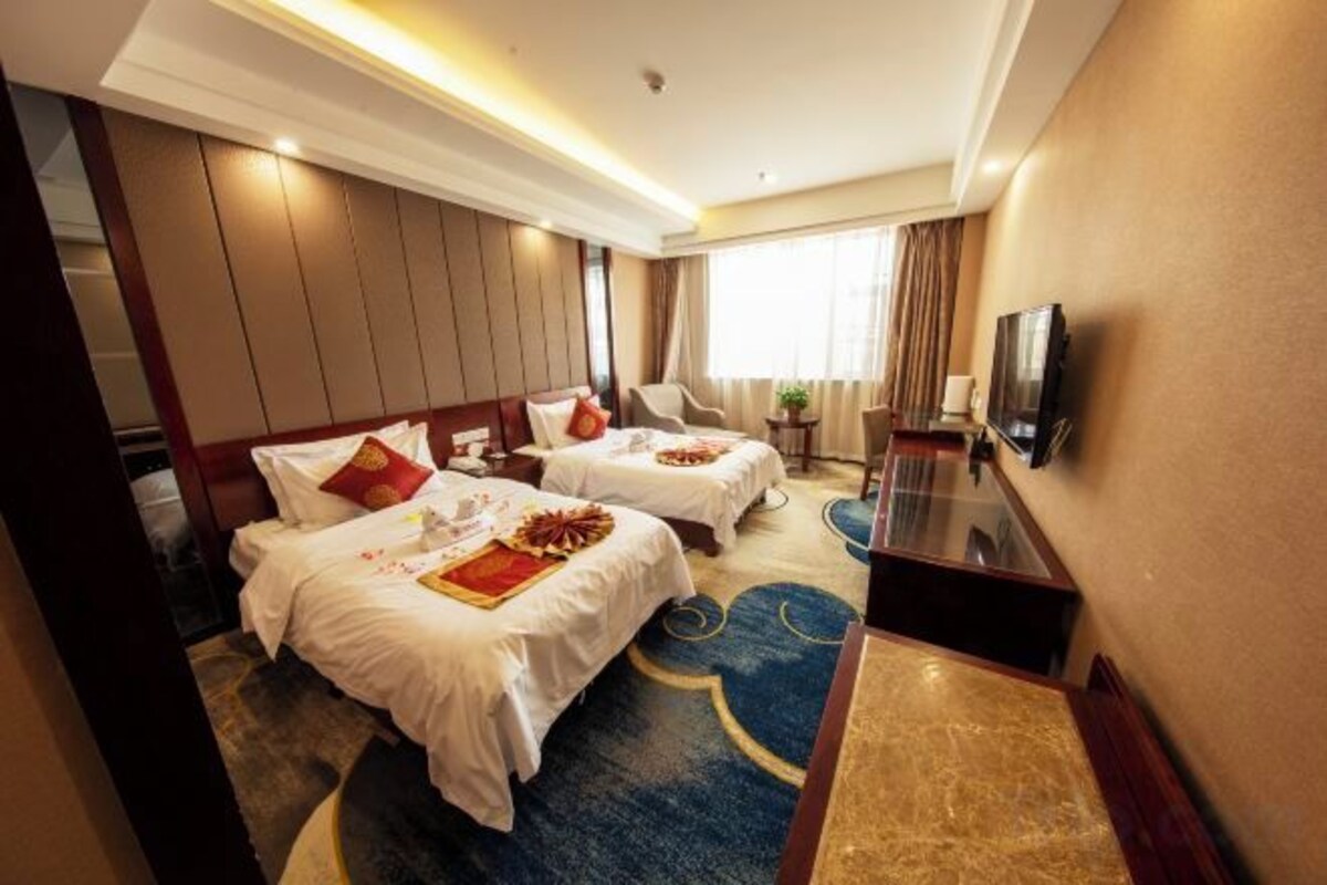 Une chambre d’hôtel avec deux lits, un téléviseur à écran plat et une grande fenêtre.