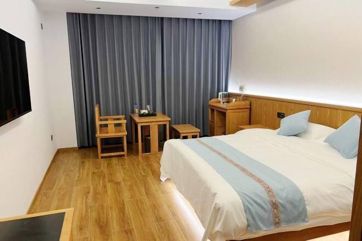 Habitación de hotel con cama, escritorio, silla, mesita y televisor.