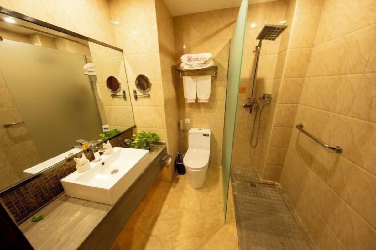 A modern bathroom with a large mirror, a white sink, a toilet, and a shower area.