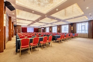 A conference room with rows of tables and chairs, large windows, and a high ceiling with chandeliers. - Han Tang · Grand Hotel (Dunhuang)