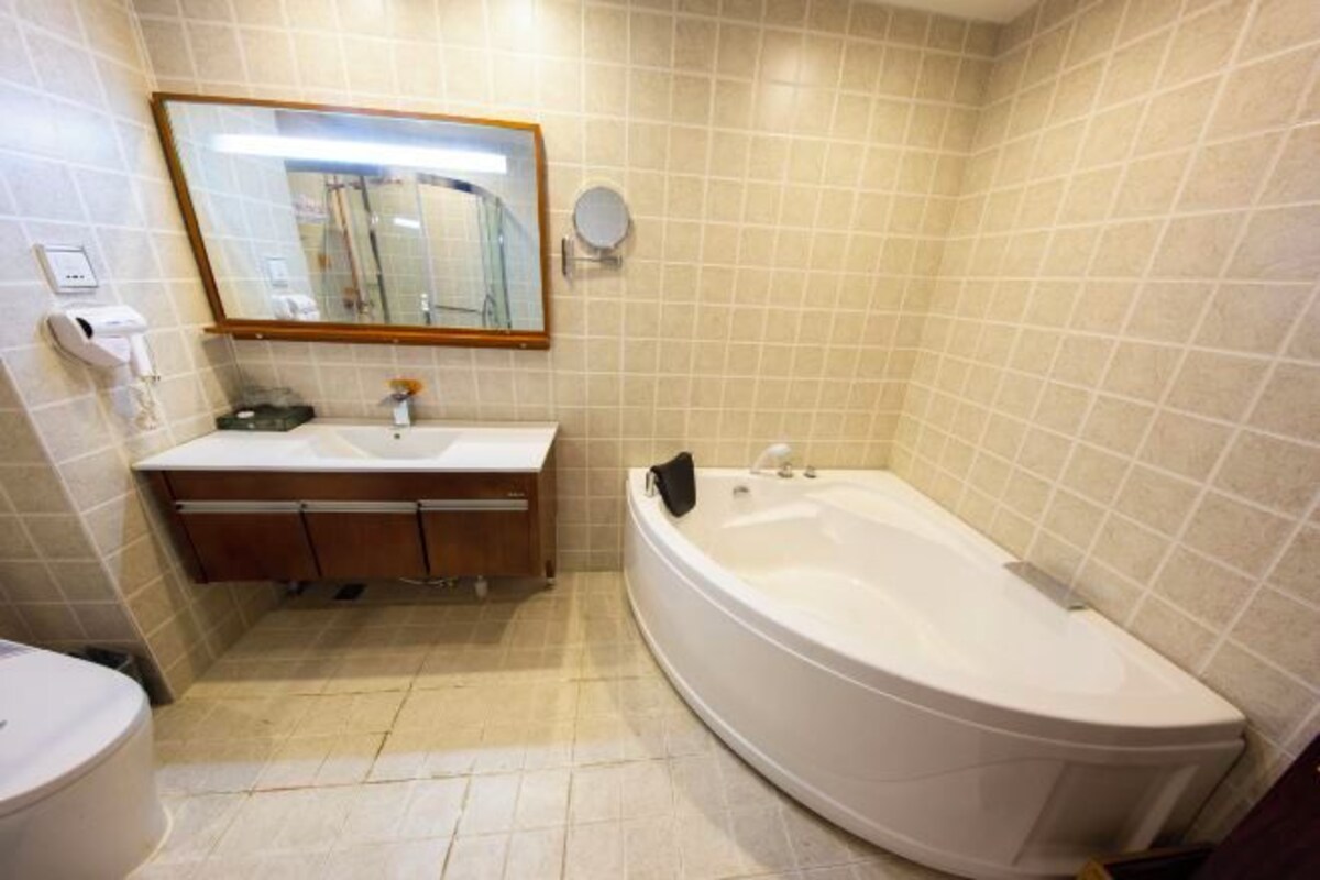 A bathroom with a sink, mirror, and bathtub.