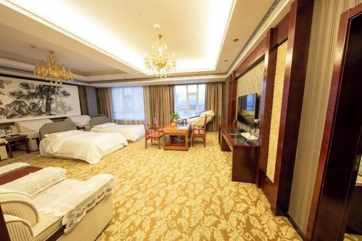 Habitación de hotel con dos camas, una mesa de comedor, un televisor y un ventanal grande.