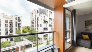 Un apartamento moderno con balcón, un sofá gris y vistas a otros edificios.