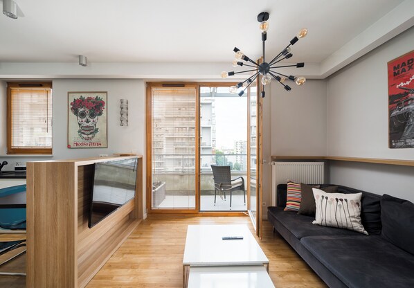 A modern living room with a black sofa, a white coffee table, and a TV on a wooden stand.
