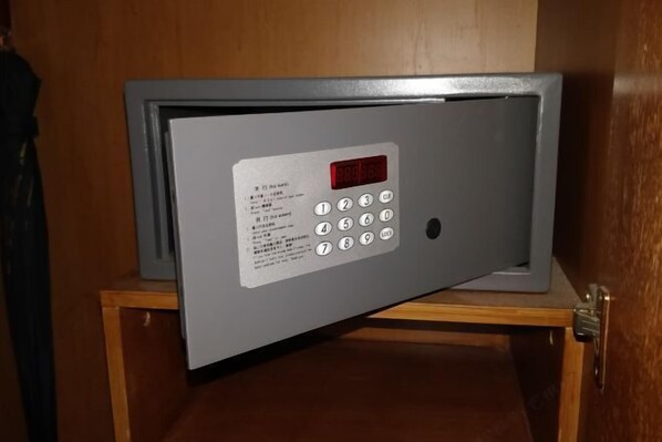 Ein Tresor mit digitaler Tastatur und Bildschirm, an einem Holzschrank befestigt.