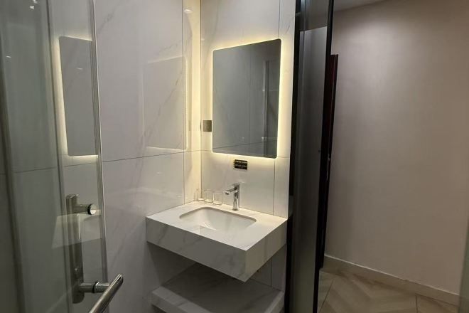 A modern bathroom with a glass shower enclosure, a white sink, and a mirror.