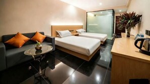 Ein modernes Hotelzimmer mit einer Couch, zwei Betten, einem kleinen Tisch und einem Schreibtisch.