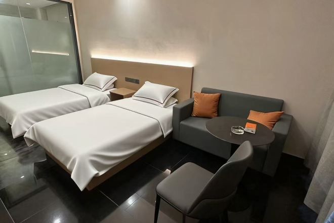 A hotel room with two beds, a sofa, a small table, and a chair.