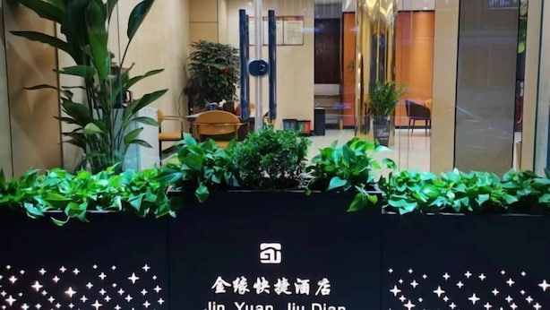 Eine Hotelhalle mit Empfangstresen, Topfpflanzen und einer schwarzen Wand mit weißer Schrift.