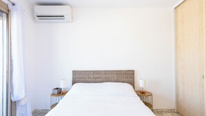 Habitación de hotel con una cama grande, dos mesitas de noche con lámparas, un equipo de aire acondicionado y un armario de madera.