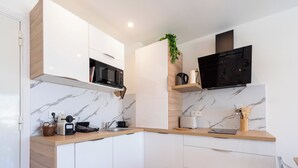Una cocina moderna con armarios blancos, salpicadero de mármol y encimera de madera.