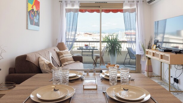 Una sala de estar moderna con comedor, un sofá, un televisor y un balcón con vistas.