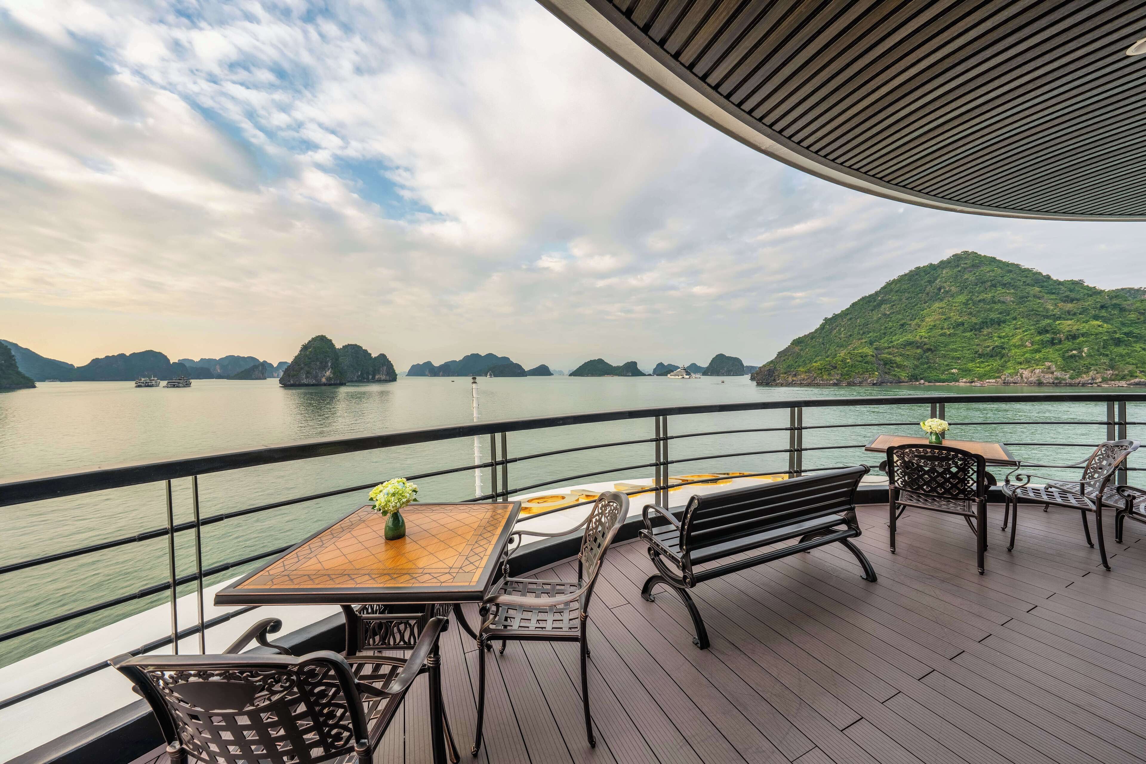 Eine Terrasse mit Tisch und Stühlen mit Blick auf ein Gewässer und entfernte Inseln.
