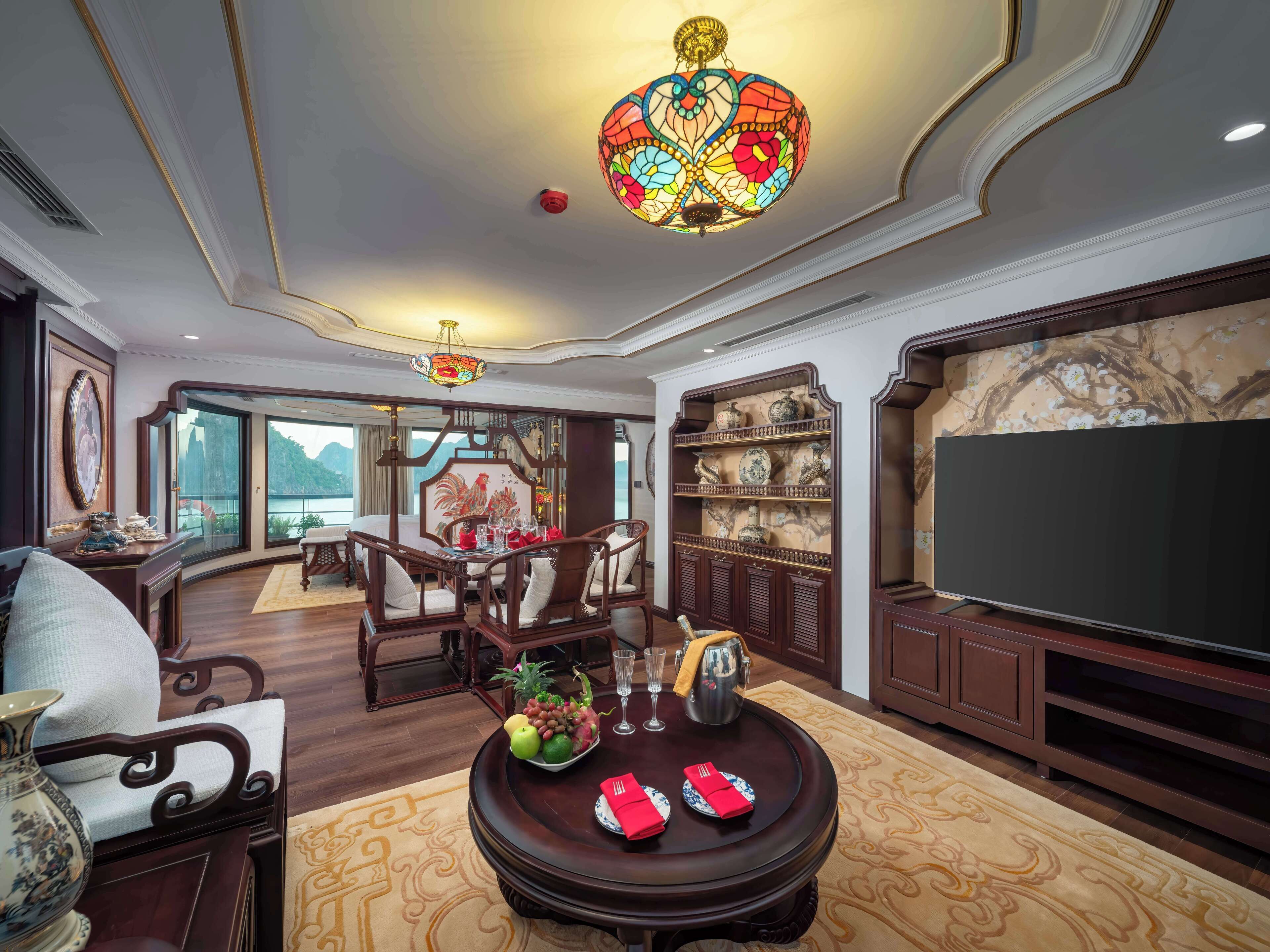 A traditional-style living room with a dining area, a large TV, and a decorative chandelier.