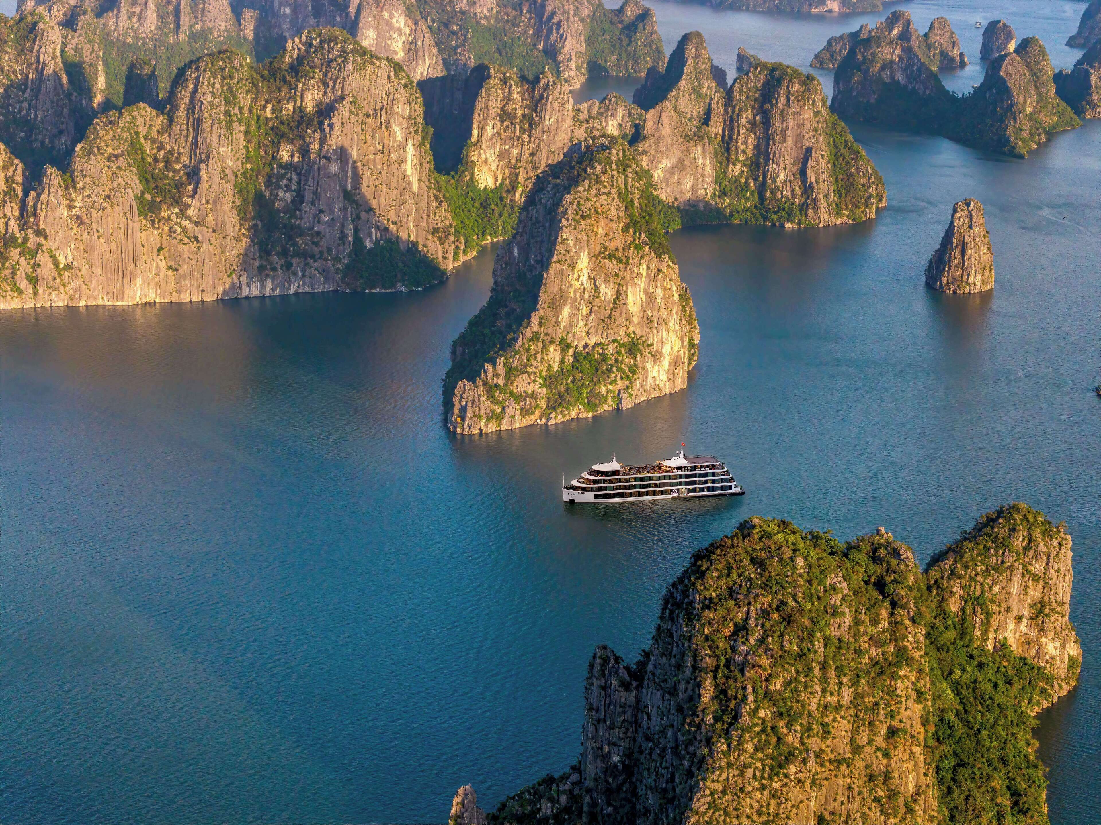 Un crucero navegando entre un grupo de islas de piedra caliza, rodeado de aguas tranquilas.