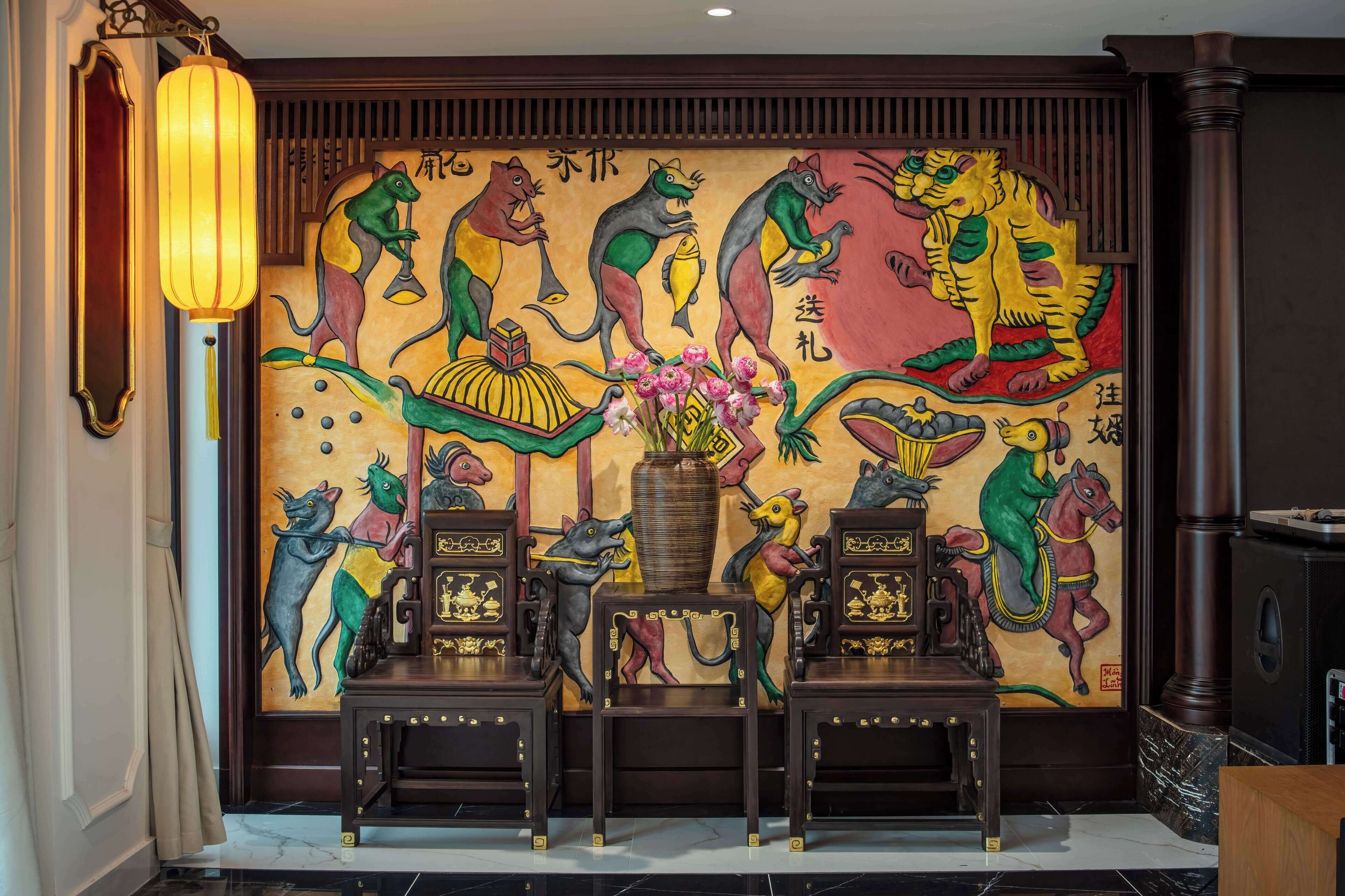 Un mural con varios animales y caracteres chinos, un farol tradicional y dos sillas ornamentadas.