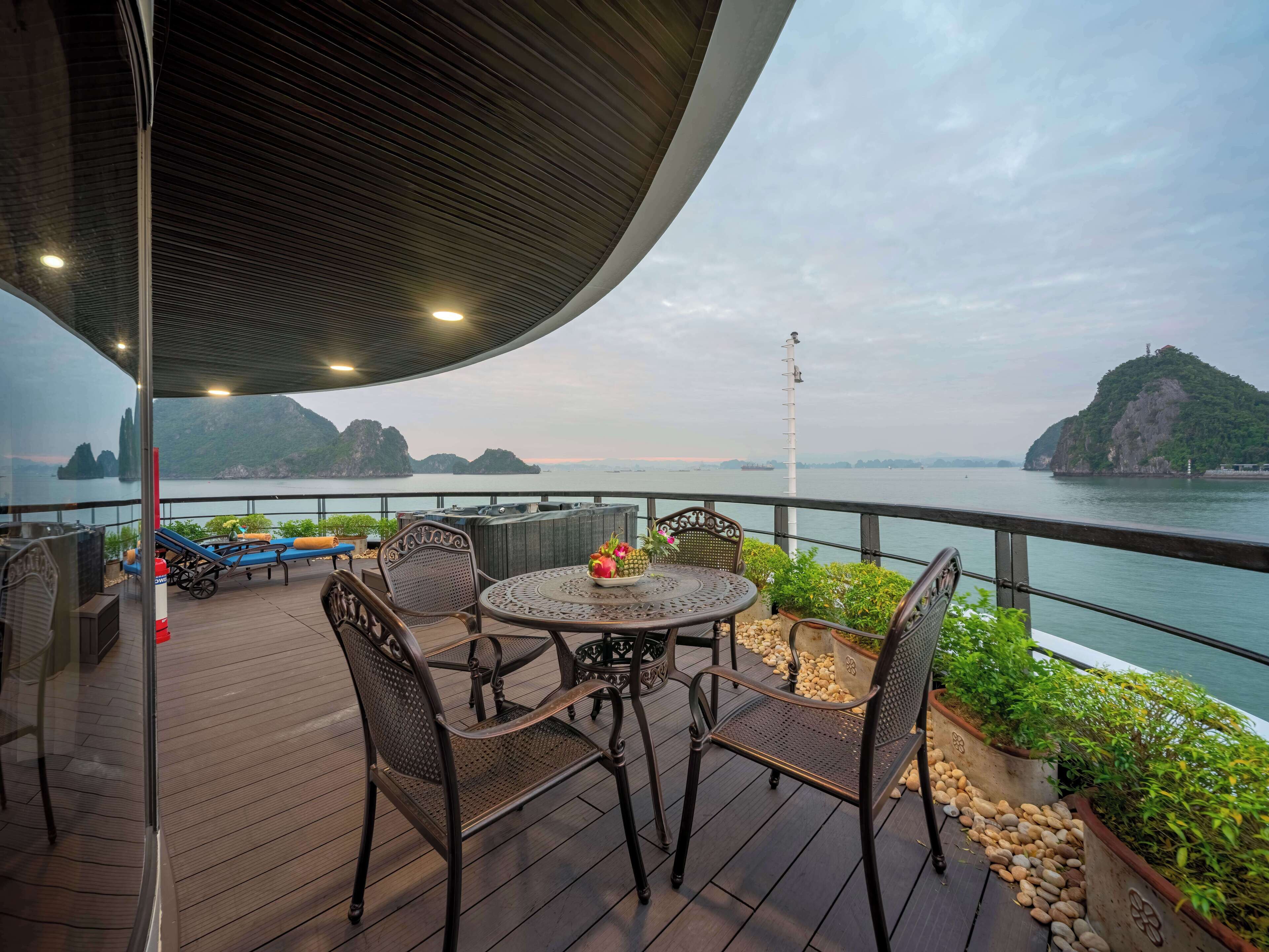 Une terrasse dotée d’une table ronde et de chaises, offrant une vue sur une étendue d’eau parsemée d’îles au loin.