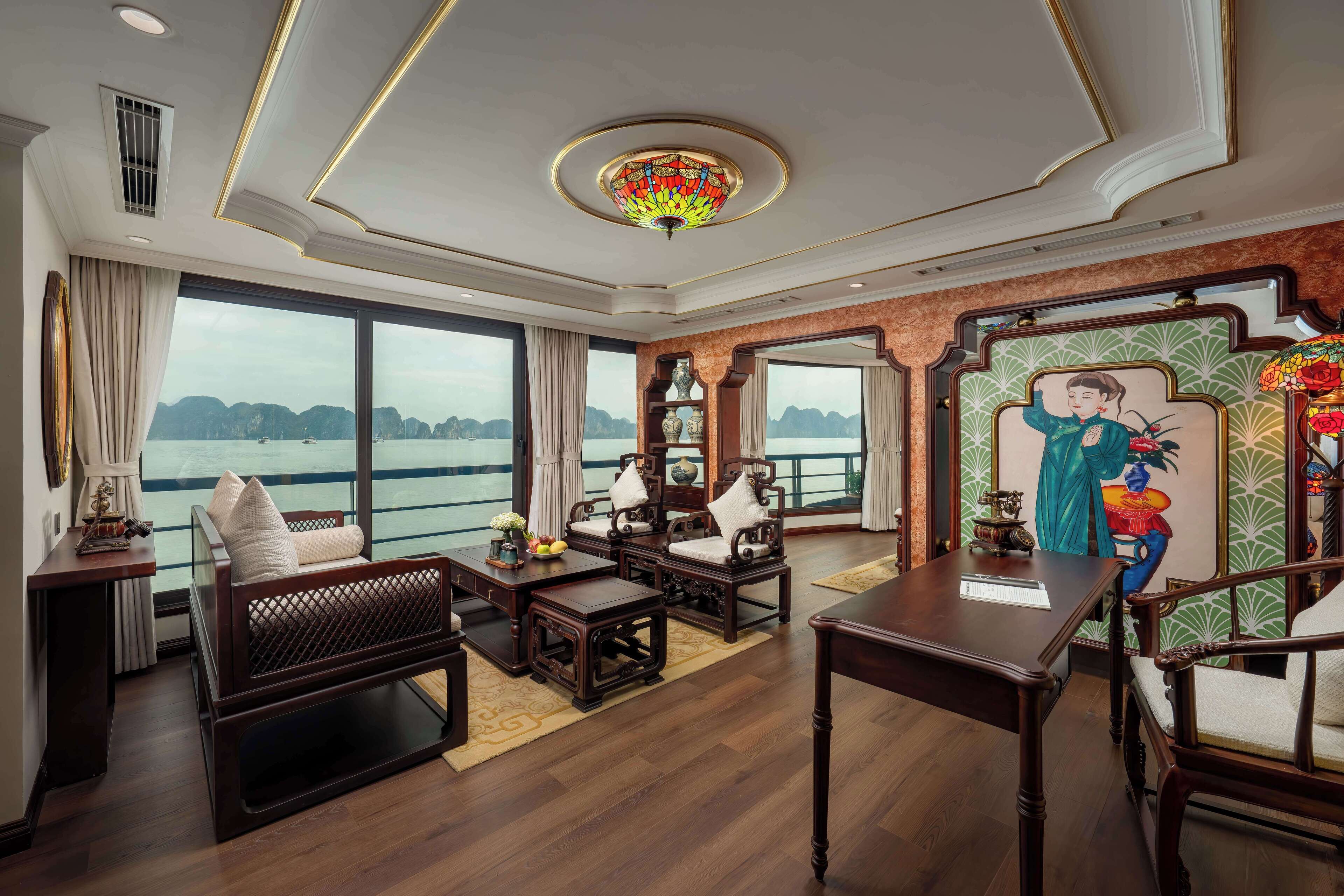 A spacious living area with a large window offering a view of the water, wooden furniture, and a decorative ceiling light.