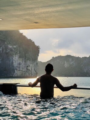 A person in a boat with a view of cliffs and water. - L'amour Cruise (Tuan Chau)