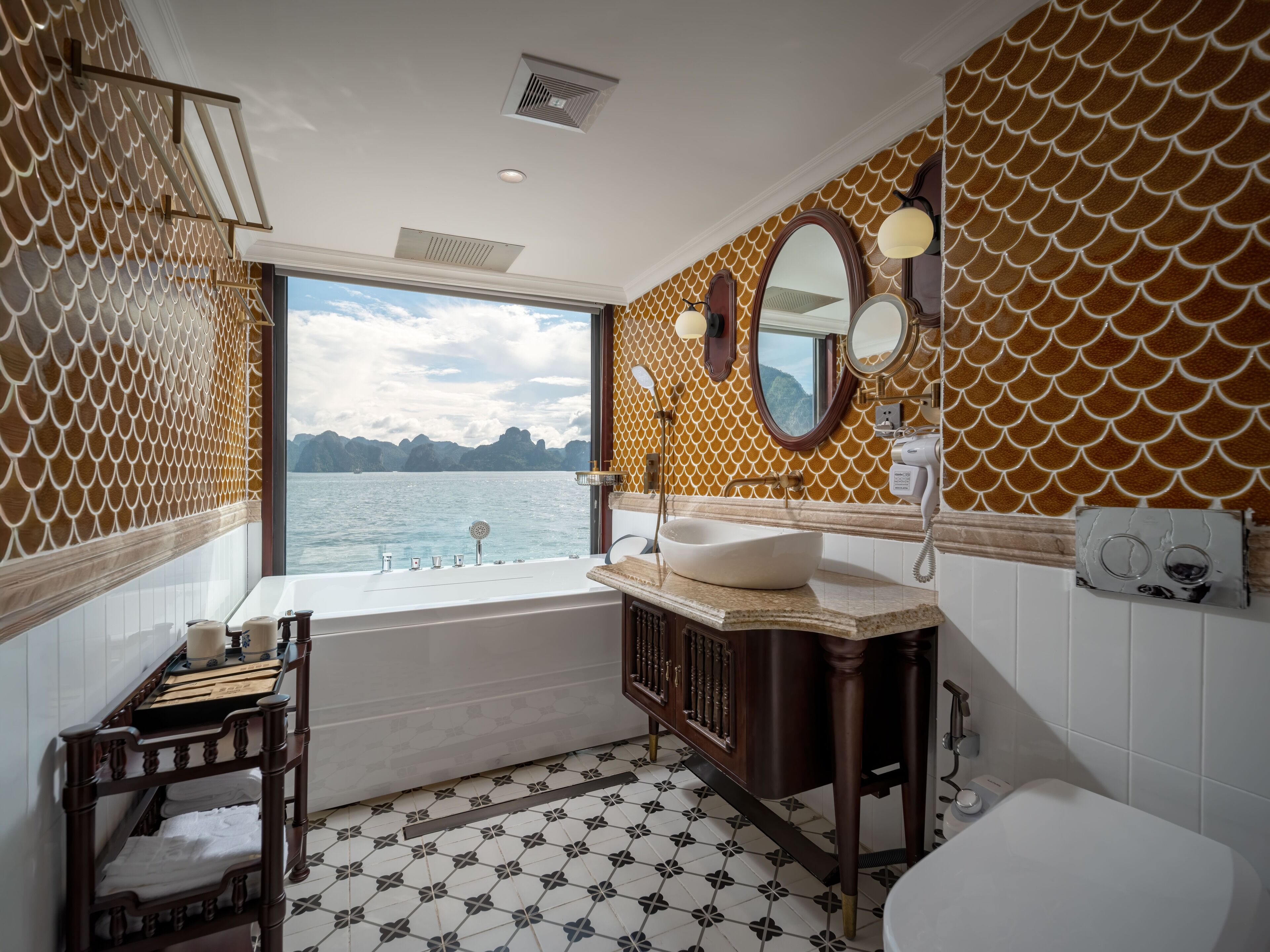Un baño con bañera, lavamanos e inodoro. Hay una ventana que ofrece vistas al agua.
