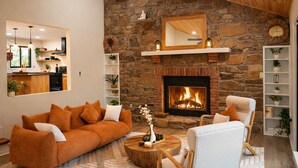 Un salon chaleureux avec une cheminée en pierre, un canapé et un fauteuil.