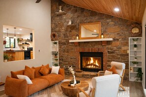 A cozy living room with a stone fireplace, a sofa, and a chair.