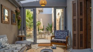 A cozy living room with a sofa, a chair, a coffee table, and a view of an outdoor patio with a table and chairs.