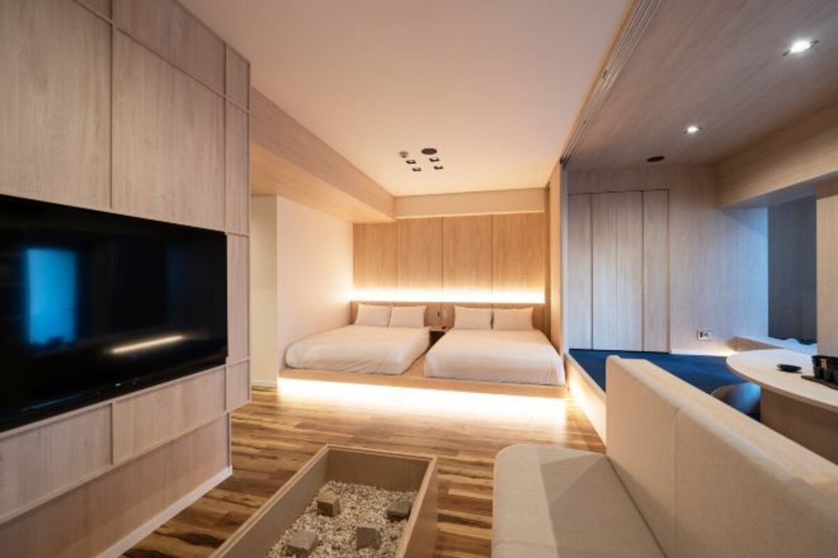 Une chambre d’hôtel moderne équipée d’une télévision à écran plat, d’un canapé, d’un lit avec deux oreillers et d’une table de chevet.