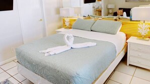 Une chambre d’hôtel avec un lit, une table de chevet, un miroir et un téléviseur.