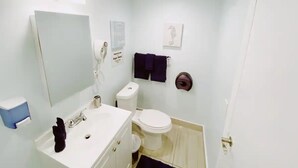 A small bathroom with a white sink, a mirror, a toilet, and a towel rack. - Comfortable SoBe Studio | Balcony | Free Beach Chairs & More (Miami Beach)